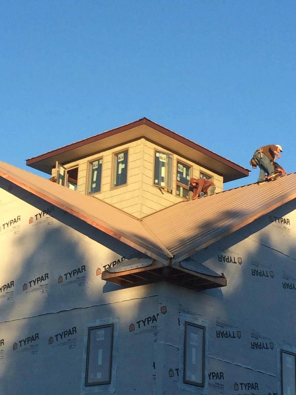 Roofers working around a rooftop cupola on a new metal roof at sunset — Roof Waterproofing in Dublin by Roofing Brothers